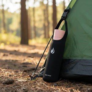 AQUA VAULT PureX Travel Sleeve with AQUA VAULT PureX Himalayan Pink Bottle leaning against a green tent in a forest.