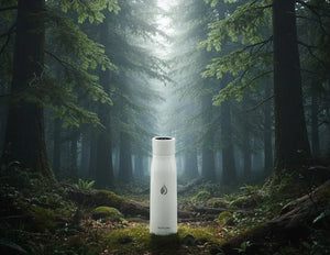 White AQUA VAULT PureX Water Bottle with a black droplet logo in a forest setting