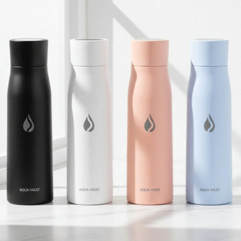 Four AQUA VAULT PureX smart water bottles in black, white, pink, and blue on a light surface with a window in the background.