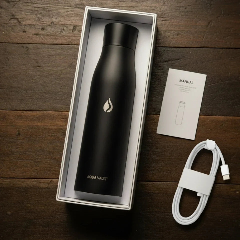 Black AQUA VAULT PureX water bottle in a box with a white cable and manual on a wooden surface