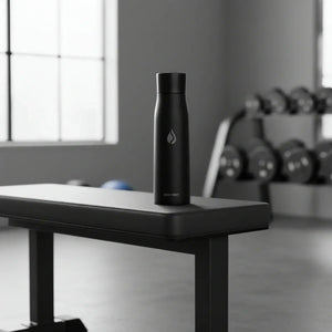 AQUA VAULT PureX black water bottle on gym bench with dumbbells in background