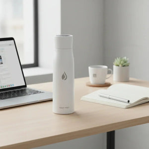 AQUA VAULT PureX Bottle on a modern desk with laptop, notebook, pen, mug, and plant