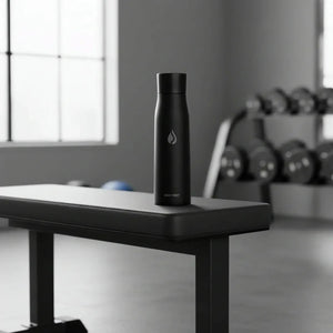 Black AQUA VAULT PureX UV-C Self-Cleaning Premium Smart Water Bottle on a table in a gym setting