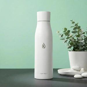 Glacier White AQUA VAULT PureX  Self-cleaning Smart Water Bottle with 'Aqua Vault' branding on a green background with a plant.