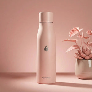 Himalayan Pink AQUA VAULT PureX  Self-cleaning Smart Water Bottle on a pink background with a plant.